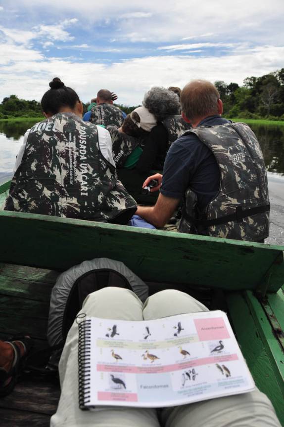 Passeio em canoa motorizada Reserva do Mamirauá, na região de Tefé, no Amazonas. No colo, livro para ajudar na identificação de pássaros